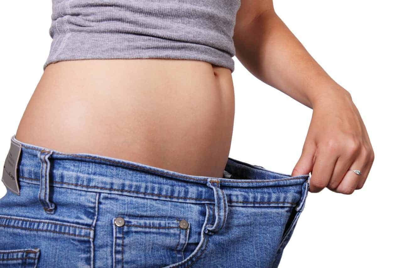 Frau hat eine viel zu grosse Jeans an, weil sie schnell abgenommen hat. Im Fitness werden dir viele solche Mythen erzählt. Leider stimmen viele dieser Geschichten rund ums Abnehmen nicht so ganz.