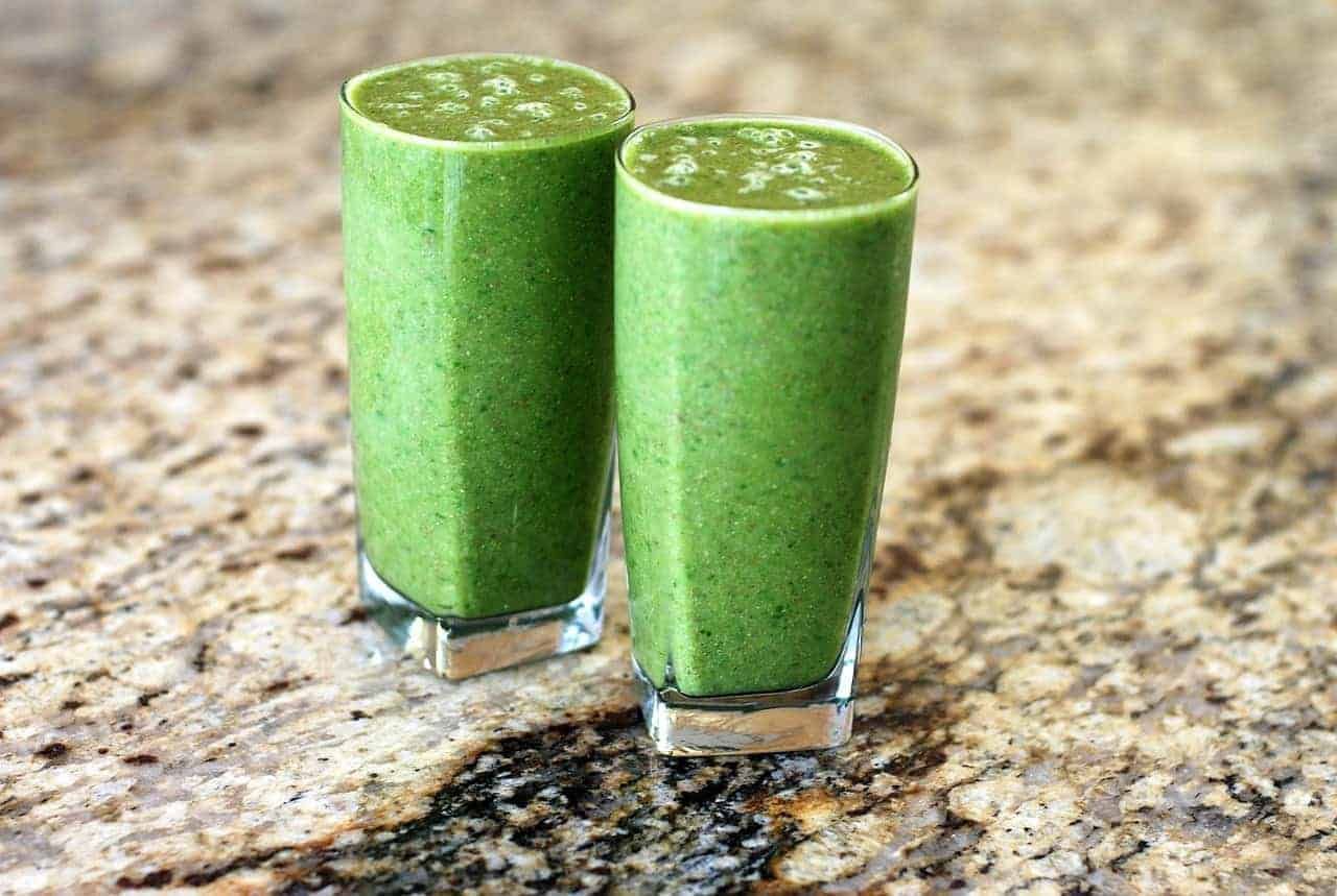 Zwei grüner Smoothies im Glas. Die starke Farbe stammt vom Chlorophyll her, einer Substanz, die unterstützend auf die Gesundheit wirkt.