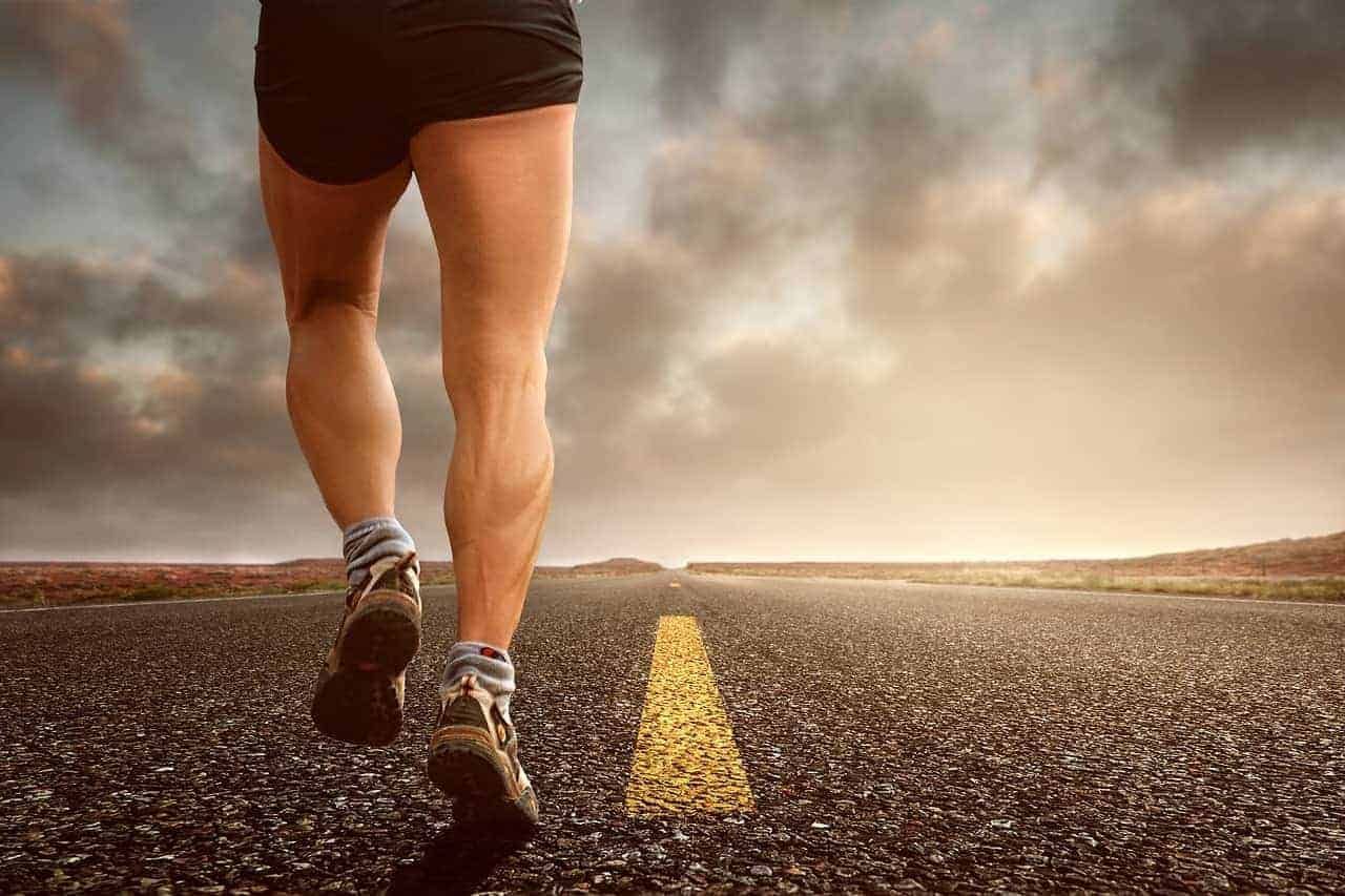 Ein Mann der beim Sonnenuntergang am Joggen ist. Für viele ist es nicht einfach nach einem harten Arbeitstag Motivation für das Training zu finden, daher läuft er ganz alleine dem Sonnenuntergang entgegen,