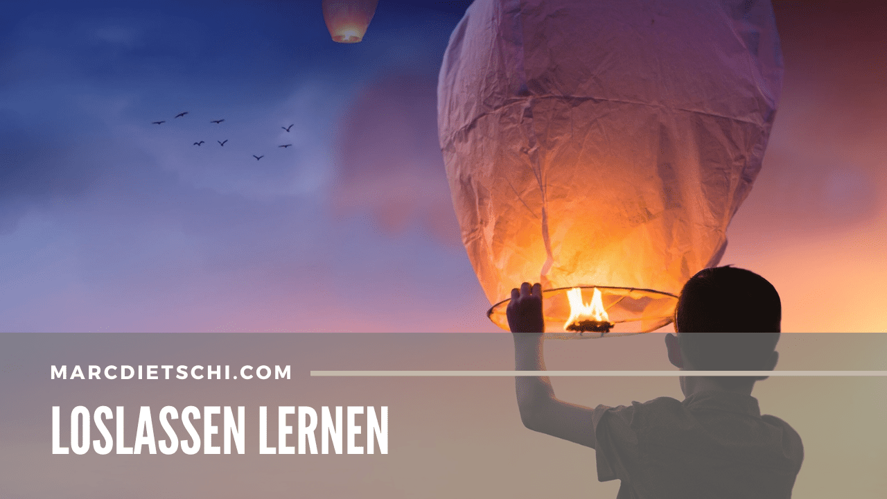 Das Bild zeigt die Silhouette einer Person, vermutlich eines Kindes, das eine leuchtende Himmelslaterne in den frühen Abendhimmel entlässt. Im Hintergrund ist ein atemberaubender Sonnenuntergang mit warmen Farben zu sehen. Über dem Bild steht in grossen weissen Buchstaben 'LOSLASSEN LERNEN', was symbolisch für das Freigeben von Sorgen oder das Loslassen von Dingen steht, die nicht mehr dienlich sind.