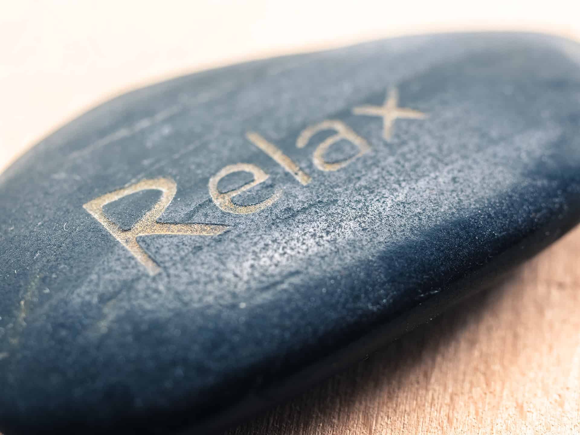 Entspannung geschrieben auf einen Stein. Diese Symbolik wird oft im Zen verwendet. Die Zenmönche sind Meister der Entspannung. Ihre Übung besteht aus einfacher Meditation und Gehen.