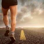 Beine einer joggenden Person auf einer Strasse mit Fokus auf Ausdauer und Fitness, inspiriert zu Bewegung und Aktivität.