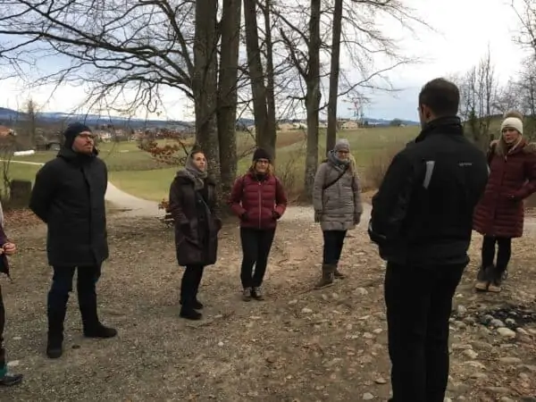 Marc Dietschi steht im Wald und unterrichtet eine Gruppe von Erwachsenen neue Meditationstechniken.
