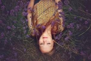 Ein Bild einer jungen Frau, die in einer entspannten, meditativen Pose auf natürlichem Boden liegt.