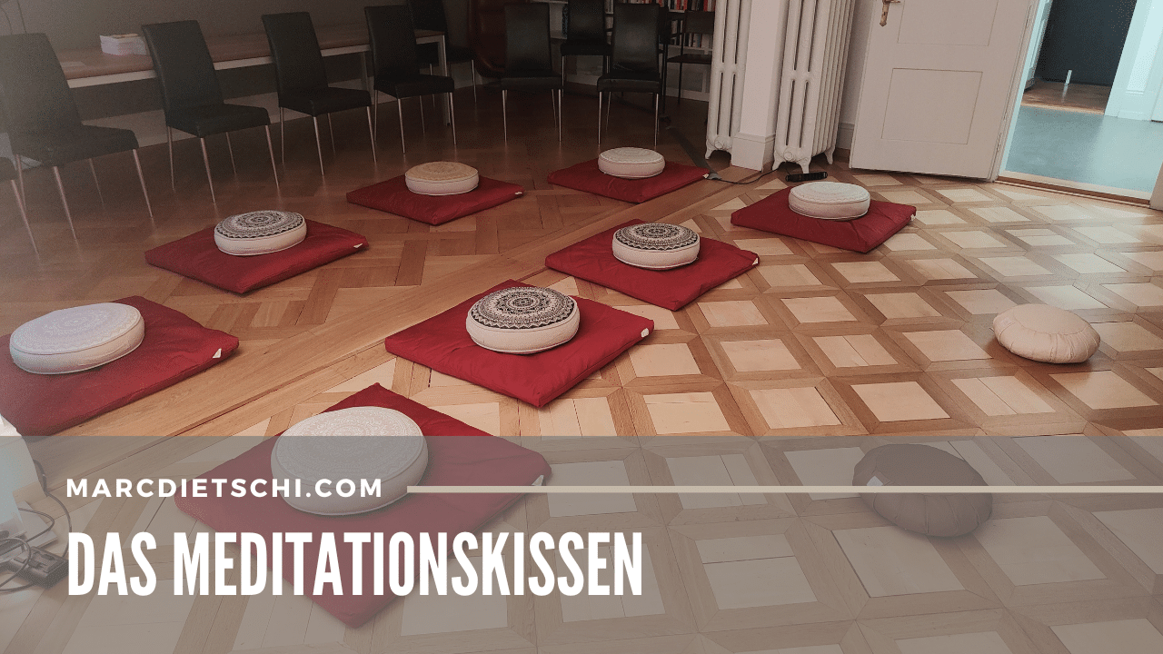 Verschiedene Meditationskissen auf einem hölzernen Boden auf roten Yoga-Kissen.